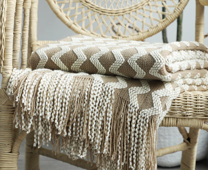 Knitted blanket with fringe draped over a wicker chair