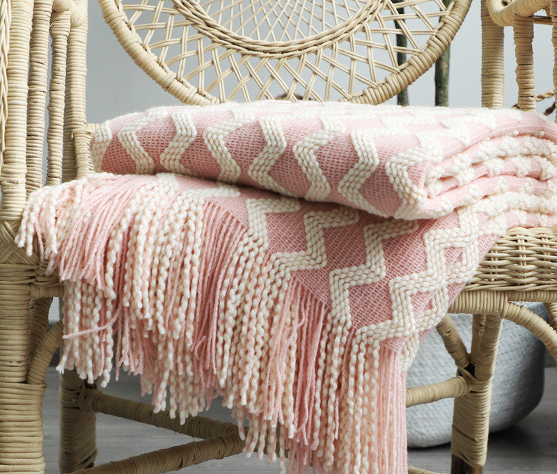 Pink and white chevron patterned blanket draped over a wicker chair.
