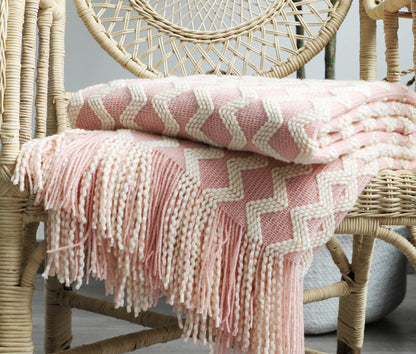 Pink and white chevron patterned blanket draped over a wicker chair.