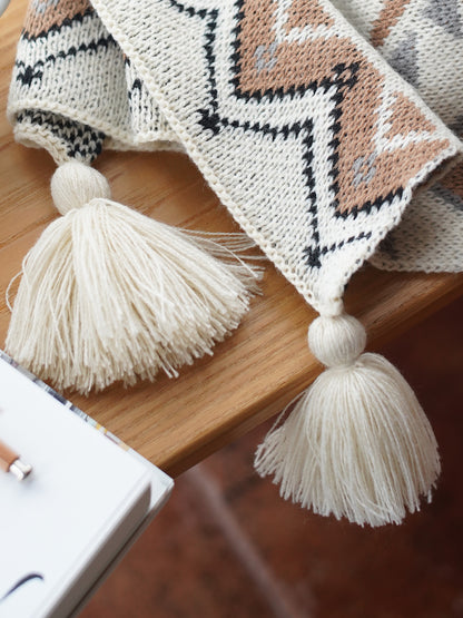 Knitted acrylic blanket with tassels on a wooden surface